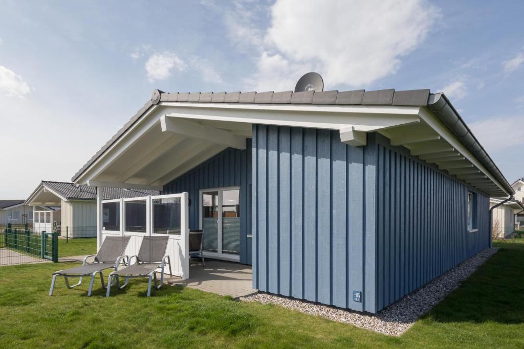 un edificio azul con techo y 2 sillas en Ferienhaus Pellworm, en Dagebüll