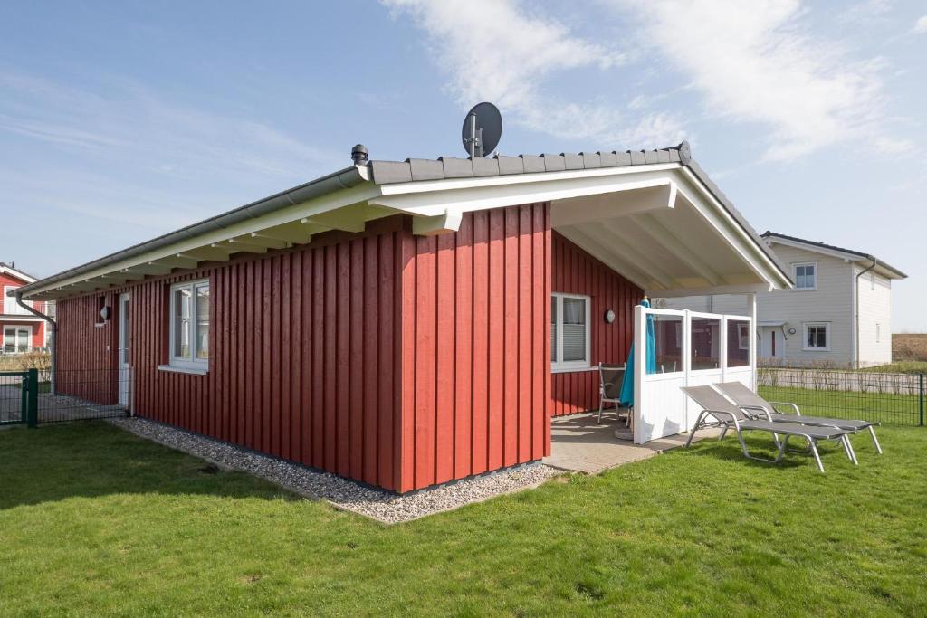 a red shed with a bench in a yard at Ferienhaus Helgoland in Dagebüll