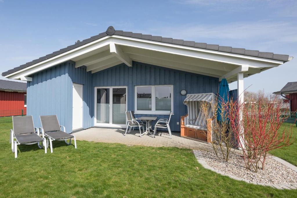 a blue shed with chairs and a table in a yard at Ferienhaus Süderoog in Dagebüll