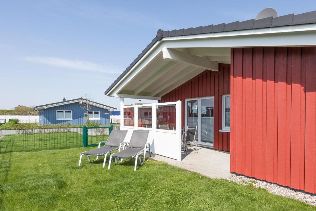 ein rotweißes Gebäude mit zwei Stühlen daneben. in der Unterkunft Ferienhaus - Sylt in Dagebüll