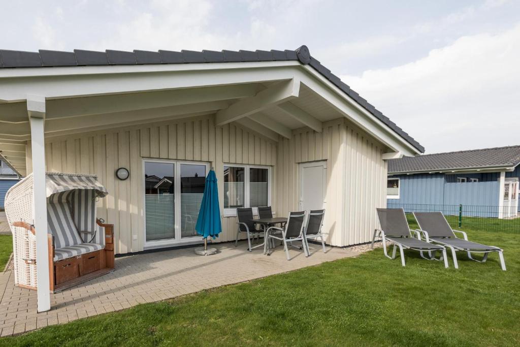 eine überdachte Terrasse mit Stühlen, einem Tisch und einem Sonnenschirm in der Unterkunft Ferienhaus Föhr in Dagebüll