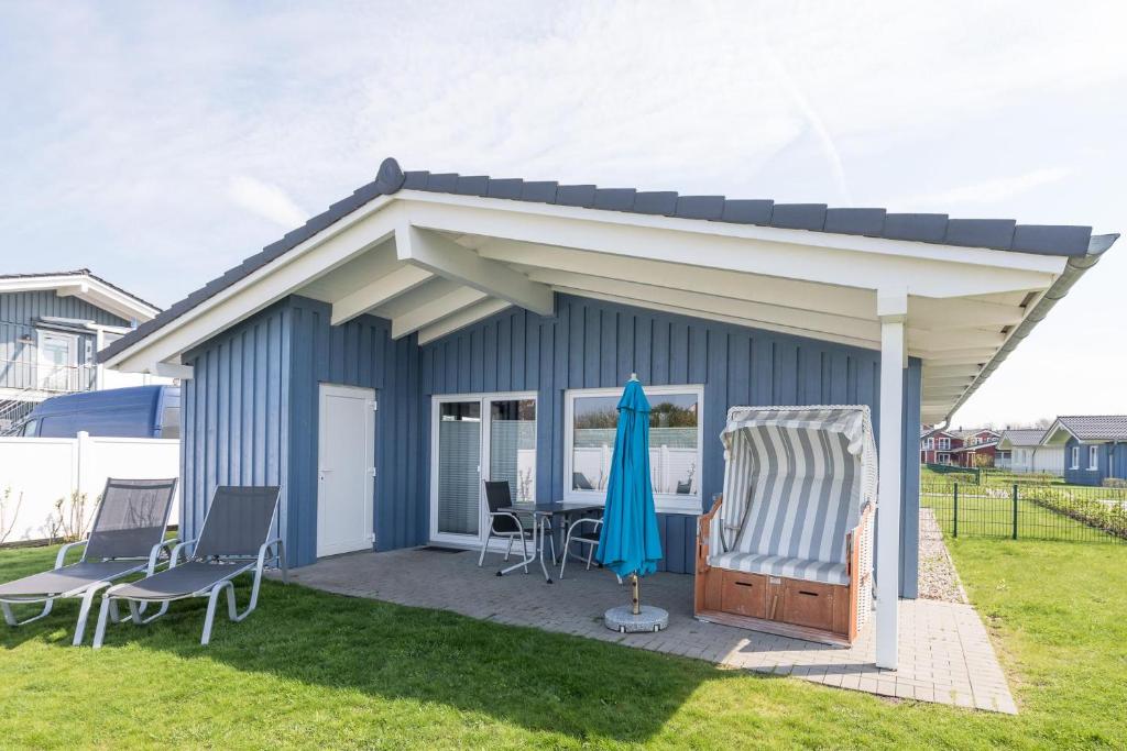 un petit hangar bleu avec une table et des chaises dans l'établissement Ferienhaus Stockente, à Dagebüll