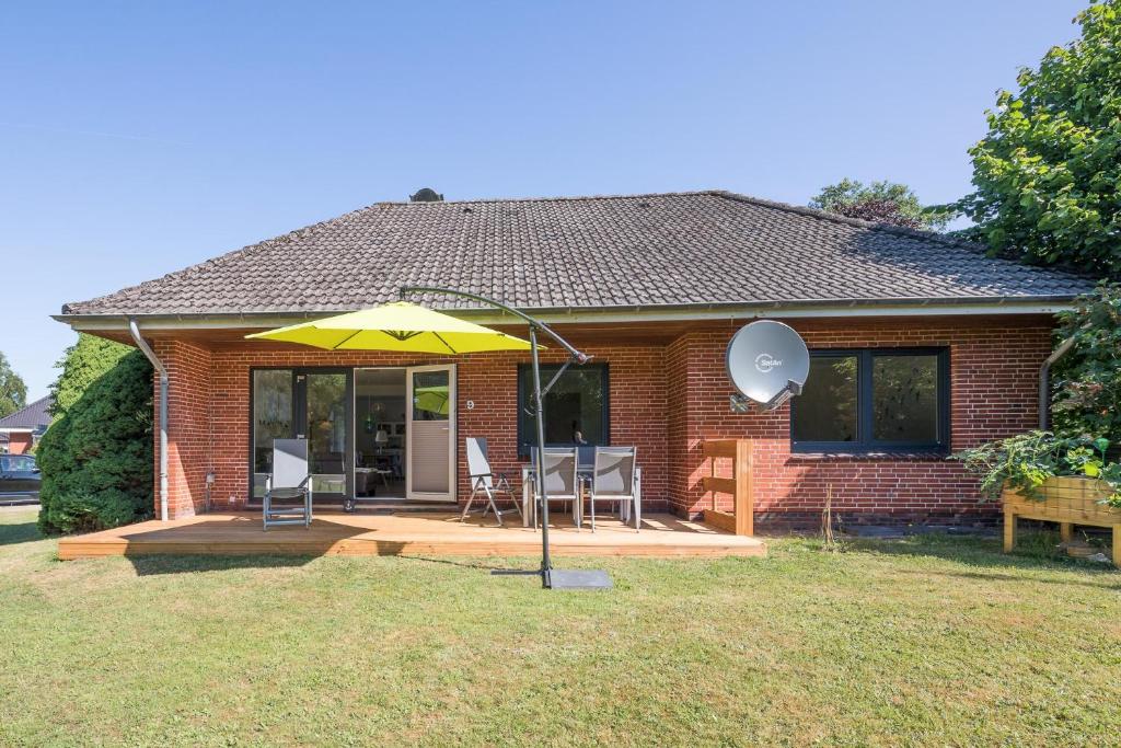 ein Haus mit einer Terrasse mit gelbem Regenschirm in der Unterkunft Villa Lütt-KEINE MONTEURE- in Husum