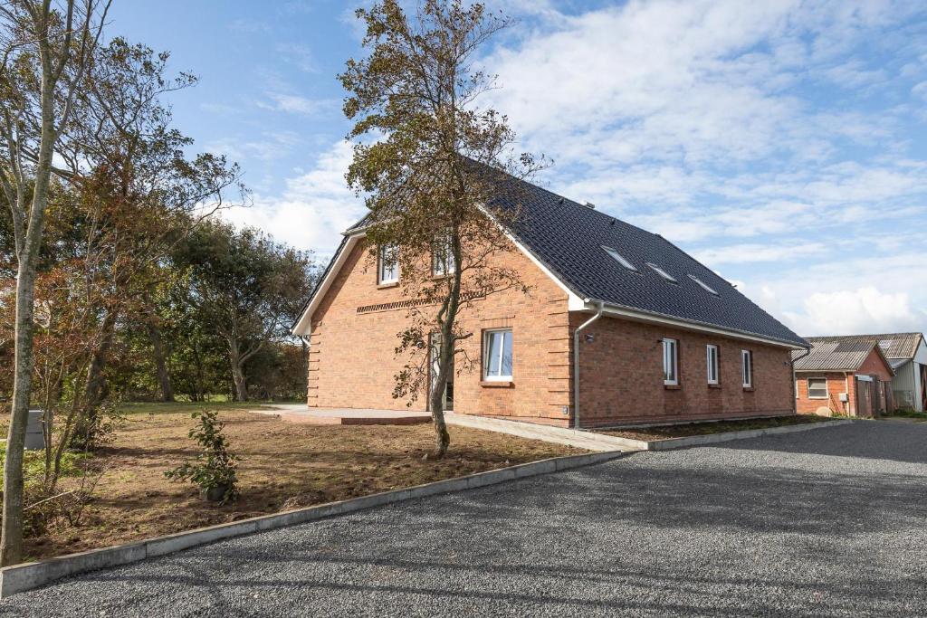 a brick house with a solar roof on a street at Achtern Diek in Dagebüll