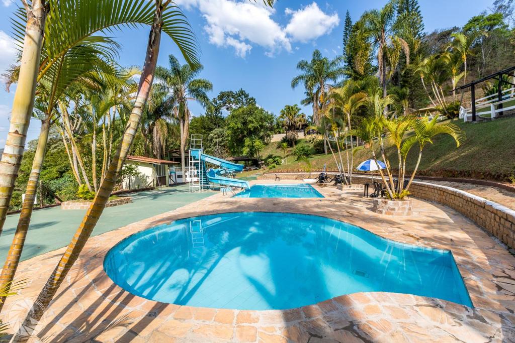 uma piscina com palmeiras num resort em Pousada Atibaia em Atibaia