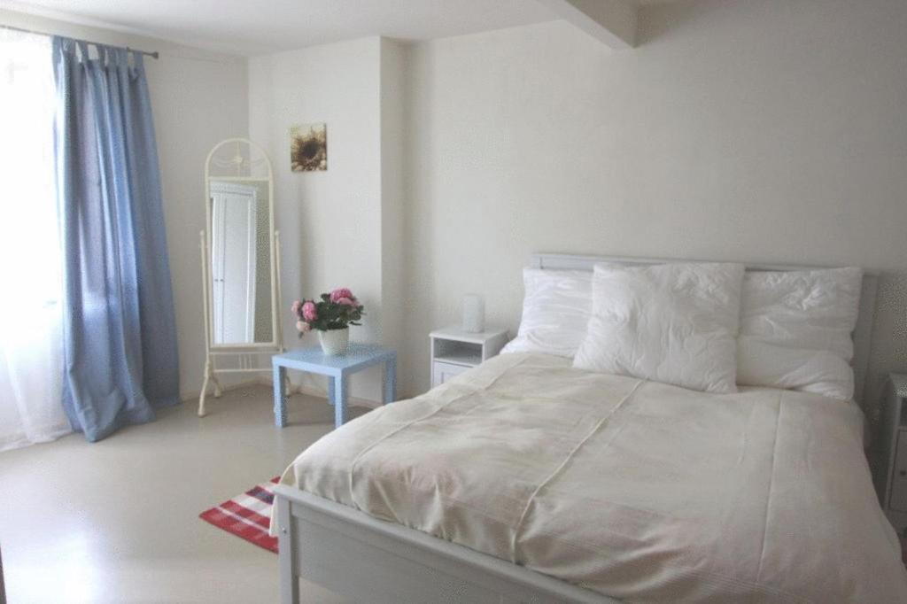 1 dormitorio con 1 cama grande con sábanas y almohadas blancas en Himmel & Hölle Ferienhäuser en Quedlinburg