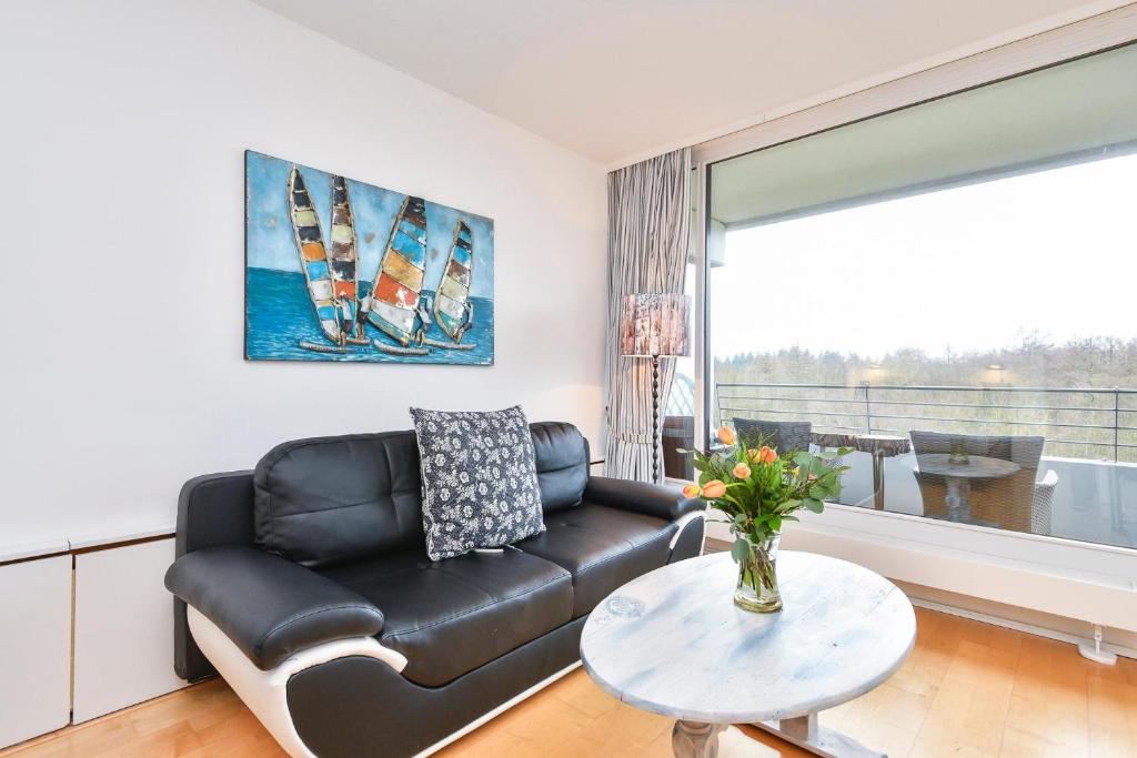 uma sala de estar com um sofá de couro preto e uma mesa em Appartement 718 em Timmendorfer Strand