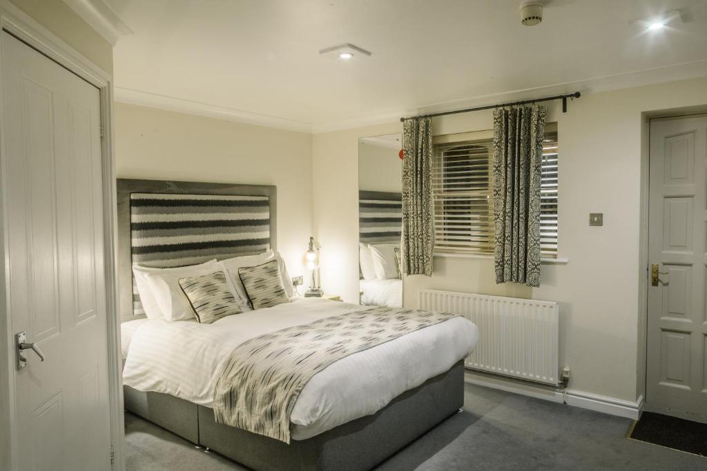 um quarto com uma cama grande e uma janela em The Old Fourpenny Hotel em Warwick