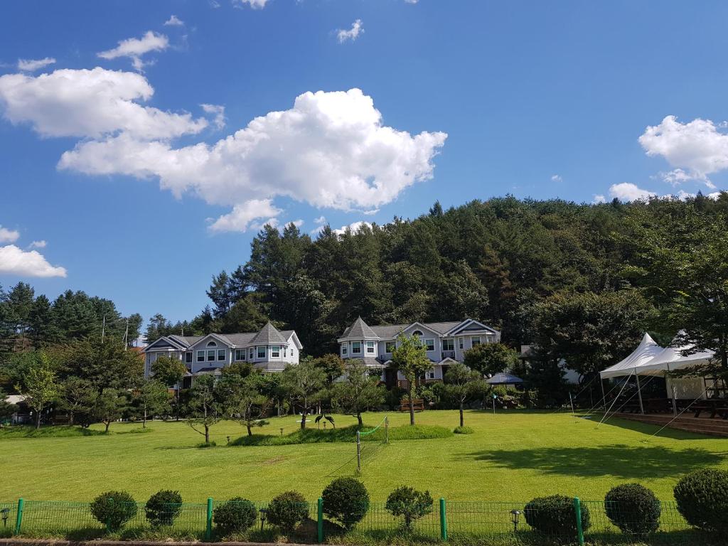 un gran campo de césped con casas en el fondo en Tomato Pension, en Hongcheon