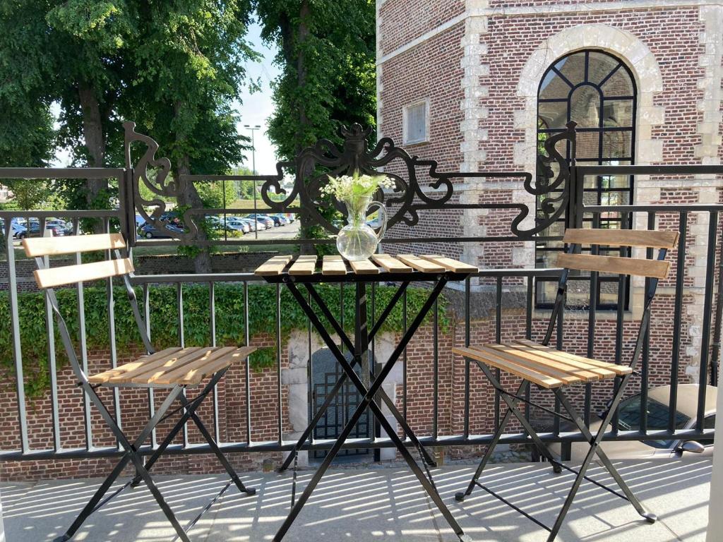 duas cadeiras e uma mesa com um vaso sobre uma cerca em Le petit béguinage em Tongeren