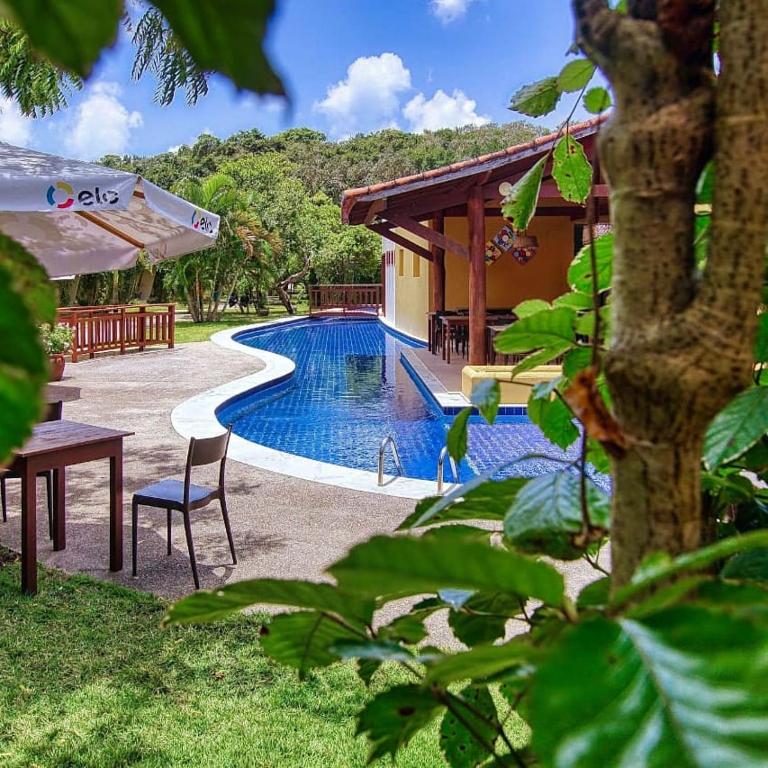 a pool with a table and a chair next to a house at Bosque da Praia Chalé 5 in Pipa