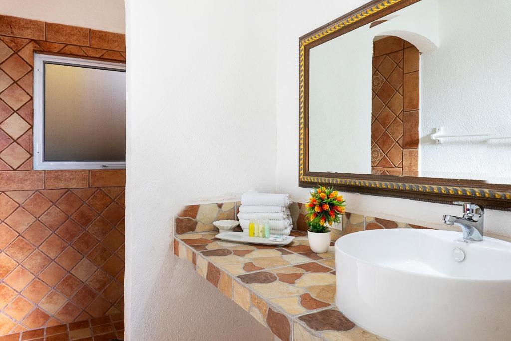 
a bathroom with a sink, mirror, and bathtub at Caleta Tankah in Tulum
