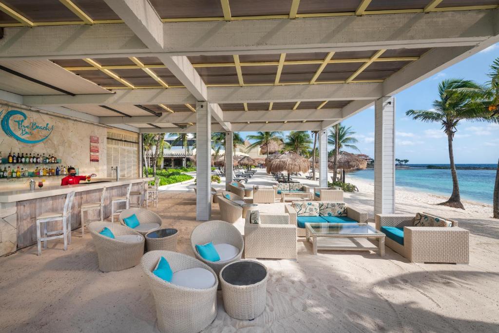 un bar en la playa con sillas y mesas en Catalonia Riviera Maya Resort & Spa- All Inclusive, en Puerto Aventuras