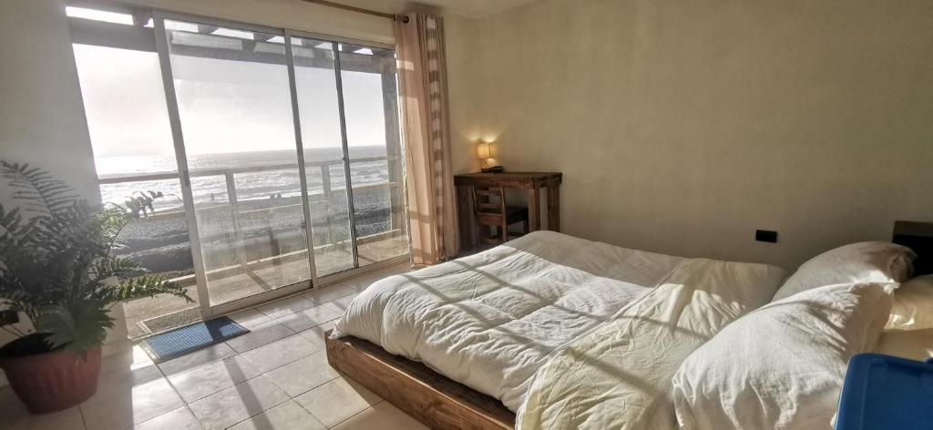 1 dormitorio con cama y ventana grande en Sudeste Hostel, en Pichilemu