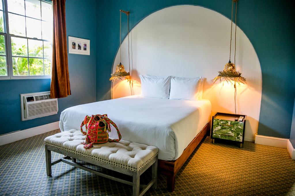 a bedroom with a large bed and a bench with a bag on it at Numero Uno Beach Apartments in San Juan