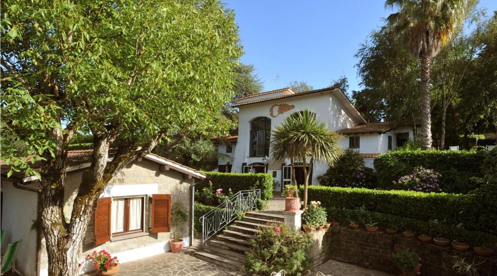 una casa bianca con una palma e scale di Hotel Villa Clementina a Bracciano