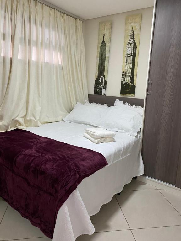 um quarto com uma cama grande com lençóis brancos e uma janela em Landscape Beira Mar Meireles em Fortaleza