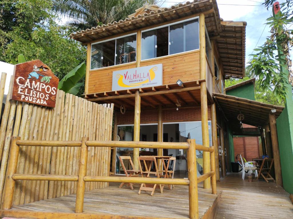 una terraza de madera con un edificio con restaurante en Campos Elísios Boipeba en Ilha de Boipeba