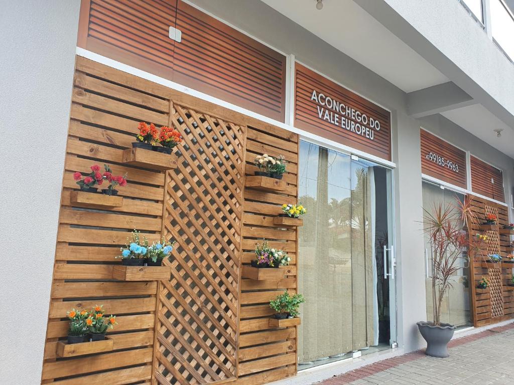 a building with a wooden wall with potted plants on it at Aconchego do Vale in Blumenau