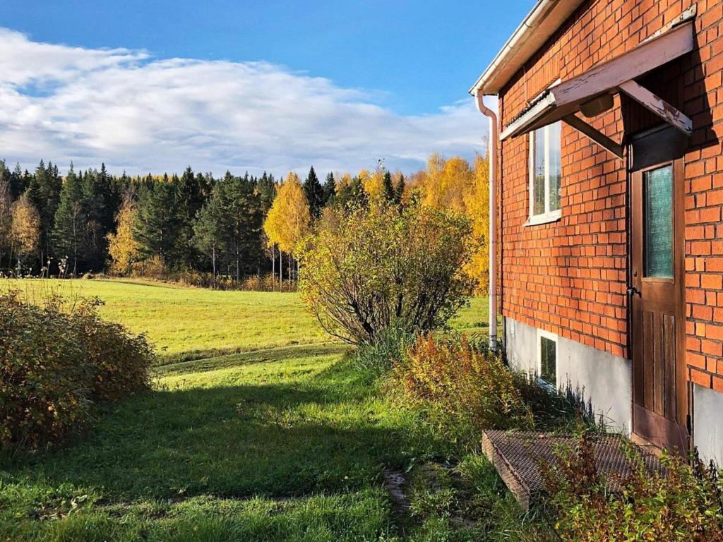 ein Backsteingebäude mit einem Feld und Bäumen im Hintergrund in der Unterkunft Holiday home KÅRBÖLE in Kårböle