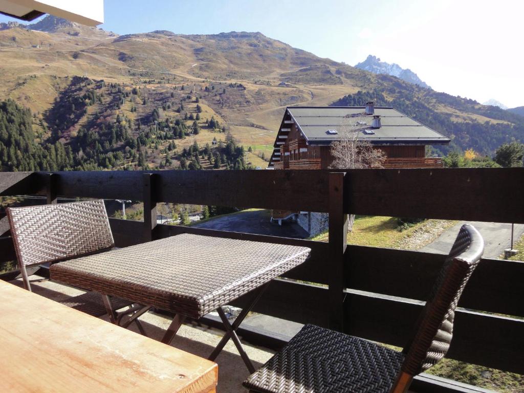 a table and chairs on a balcony with a view of a mountain at Comfortable flat close to the slopes and shops in Les Allues