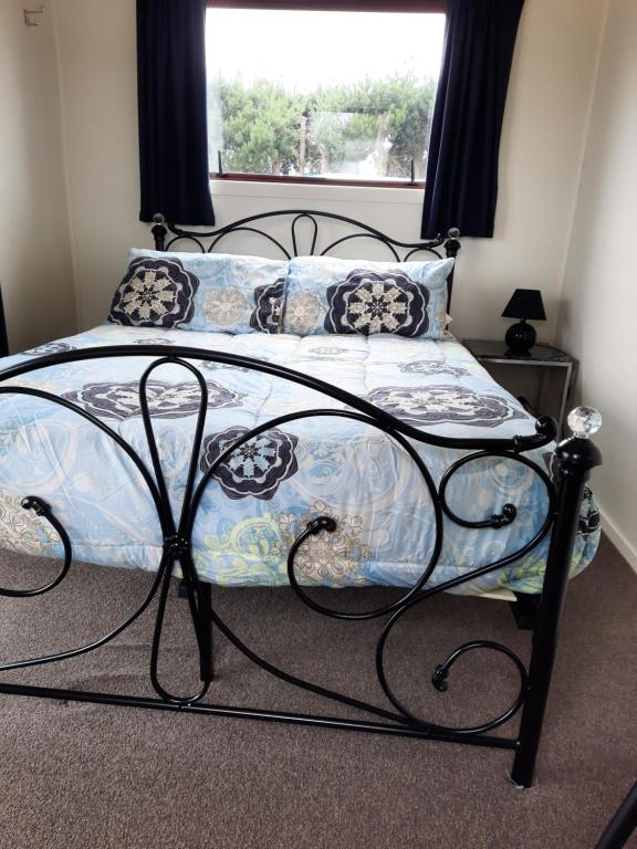 a bedroom with a large bed with a window at Glenavys Waitaki River Motor Camp in Glenavy