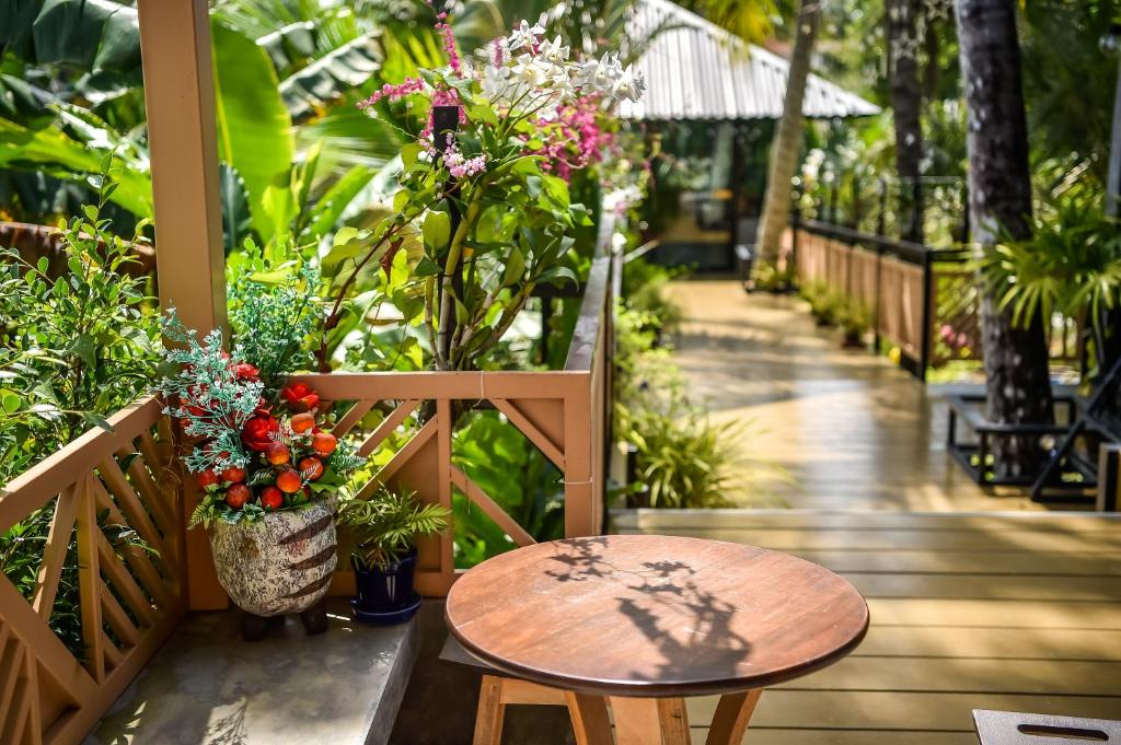 un tavolo in legno e una panca con fiori su un portico di Dee Homestay a Ban Pa Khlok