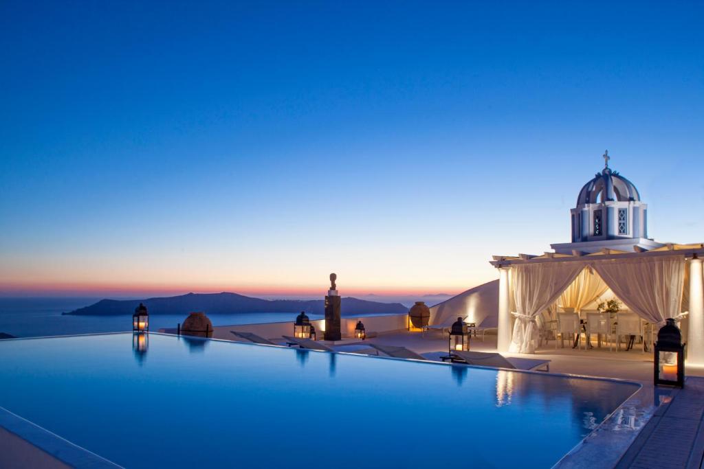 vistas a una piscina infinita por la noche con una mezquita en The Tsitouras Collection en Firostefani