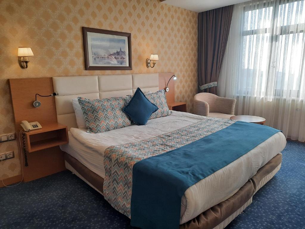 ディヤルバクルにあるPlaza Hotel Diyarbakirの大きなベッドと椅子が備わるホテルルームです。
