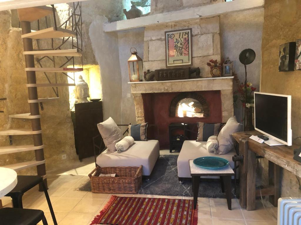 a living room with a fireplace and a tv at TROGLODYTE LOFT 2 in Thoré-la-Rochette