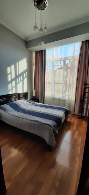 a bed in a bedroom with a large window at Apartment on Aleksandr Pushkin Street in Tbilisi City