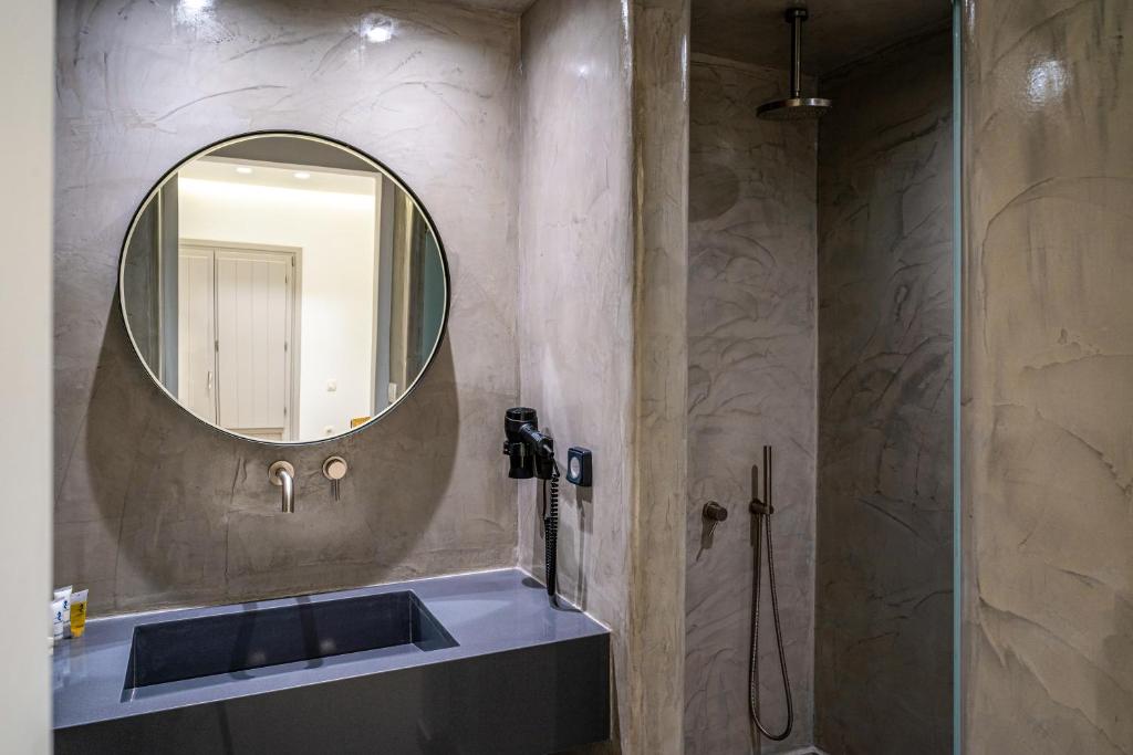 a bathroom with a sink, mirror and bath tub at Hippocampus Hotel in Kamari