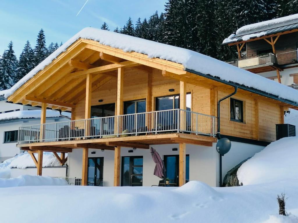 um chalé de madeira na neve com uma varanda em Chalet Rotheheim em Kirchbach