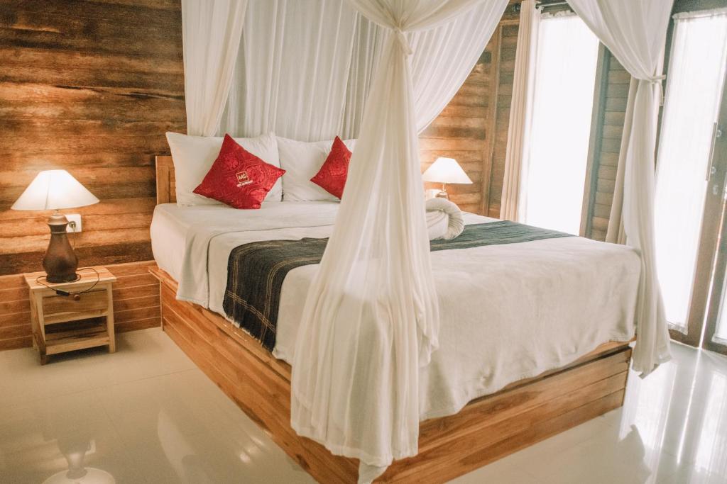 1 dormitorio con 1 cama con sábanas blancas y almohadas rojas en Mertasari Bungalows en Nusa Penida