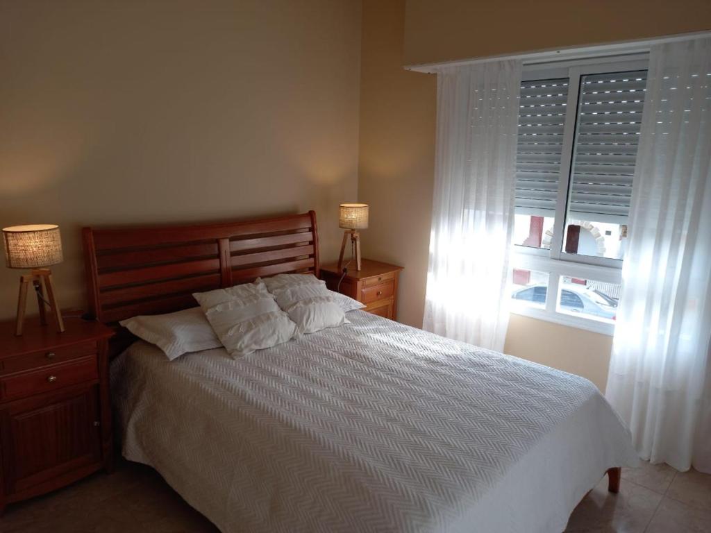 a bedroom with a white bed and a window at Departamento Necochea in Necochea