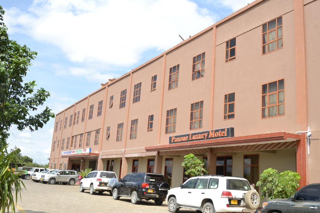 un gran edificio con coches estacionados frente a él en Panone Hotels - King'ori Kilimanjaro Airport, en Moshi