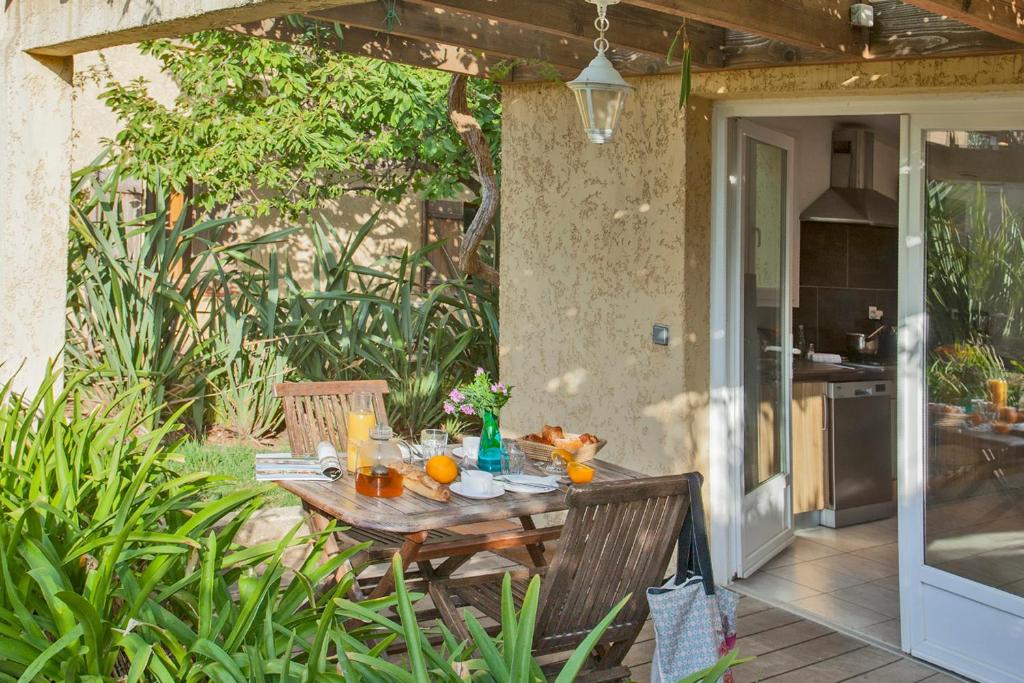 minivilla lilas indépendante à Calvi avec jardin et piscine jardin et bbq في كالفي: طاولة خشبية عليها برتقال في الفناء