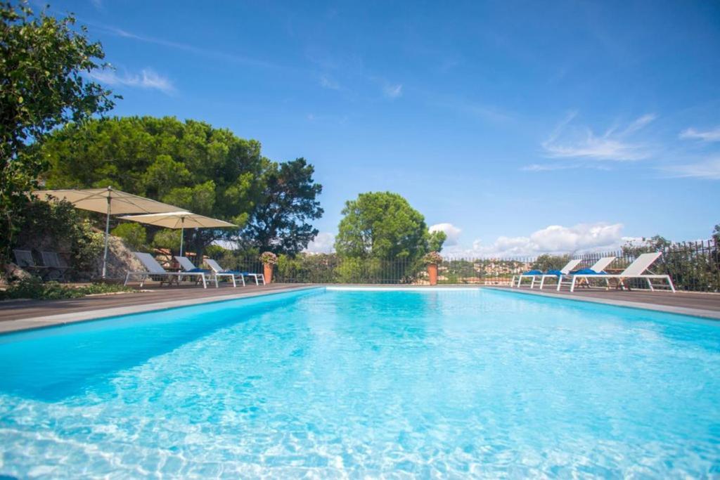 uma grande piscina com cadeiras e um guarda-sol em Villa in Calvi with warmed swimming pool garden sea view near the beach em Calvi