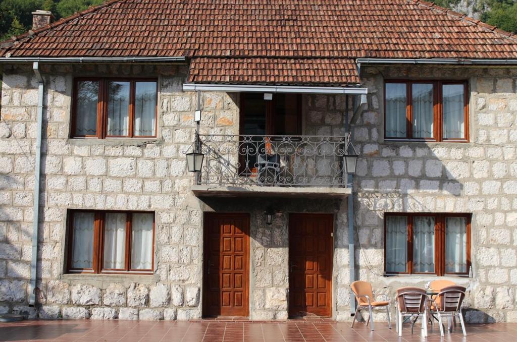 uma antiga casa de pedra com cadeiras e uma varanda em Tara Bridge Castle em Žabljak
