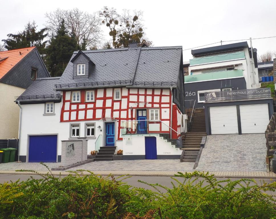 una casa roja y blanca con garaje en Hübingen Cottage, en Hübingen