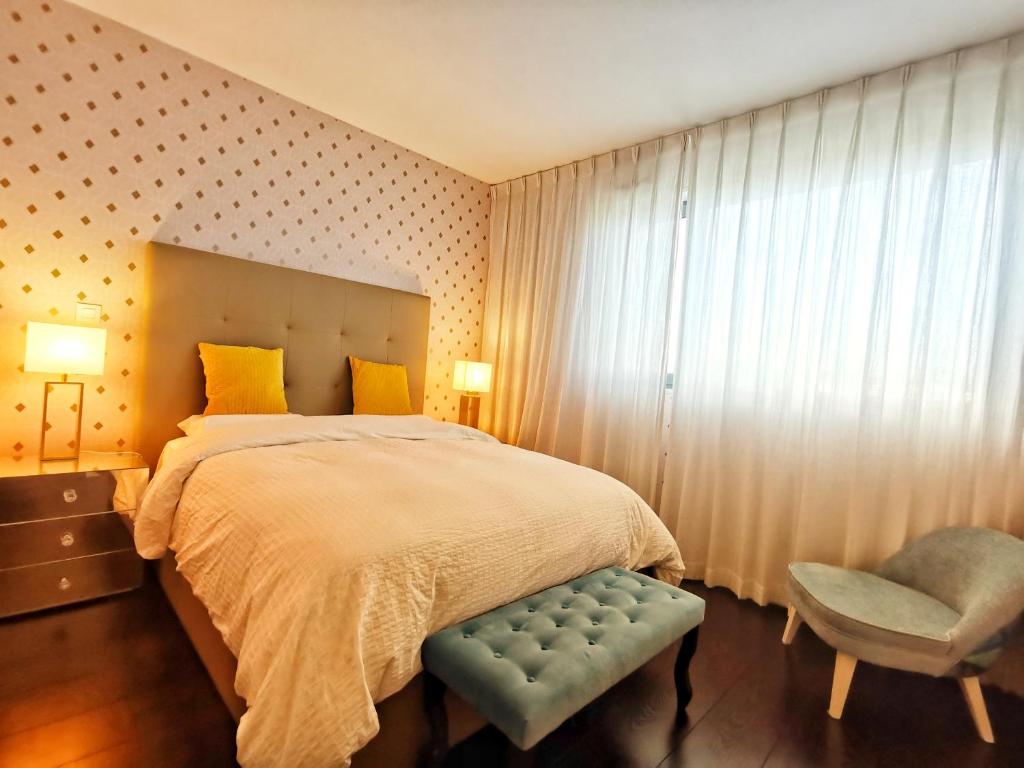 ein Schlafzimmer mit einem Bett, einem Stuhl und einem Fenster in der Unterkunft Bom dia Parque Nações LisboaX in Lissabon