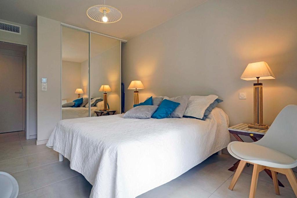 een slaapkamer met een groot wit bed en een spiegel bij Spécial Golf Appartement de 2 à 4 pers Classé 4 étoiles in Saint-Raphaël
