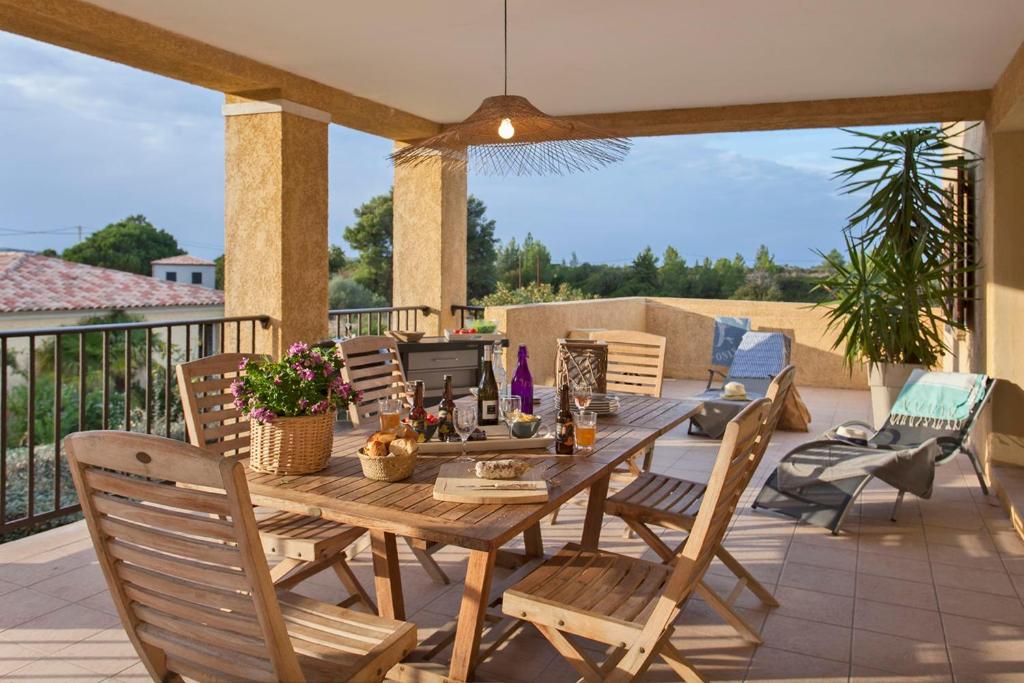 Une table et des chaises en bois sont disponibles sur la terrasse. dans l'établissement Palmier appartement de vacances 3 chambres piscine commune chauffée, à Calvi