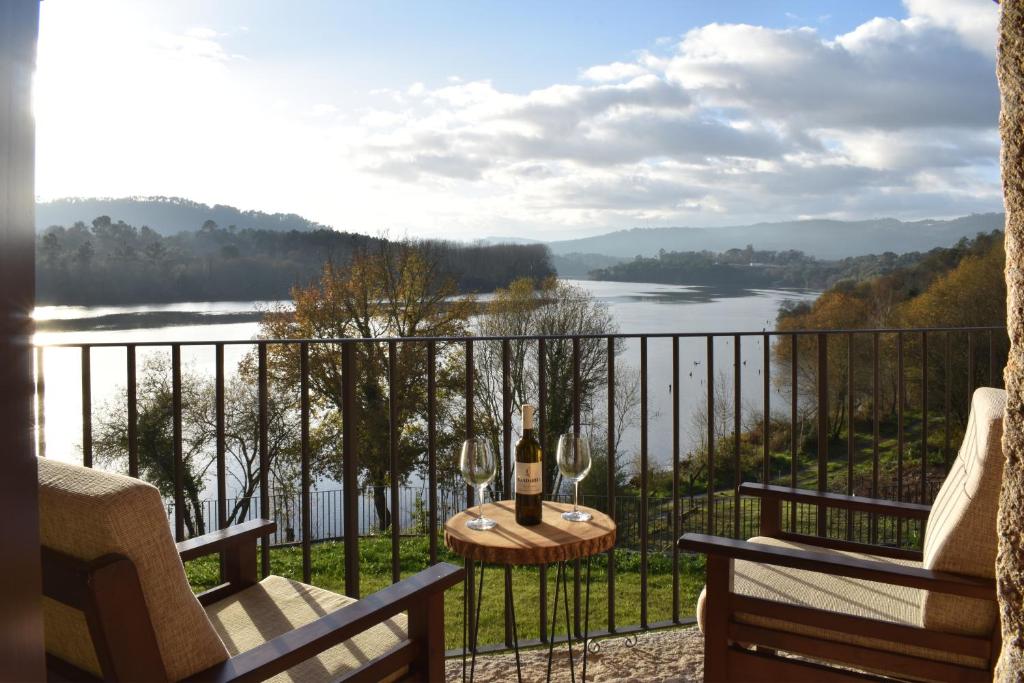 a balcony with a view of a river and a bottle of wine at Gandarela Turismo Rural in Ourense