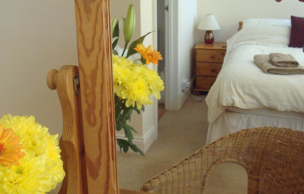 a bedroom with a mirror and a bed with yellow flowers at Harlequin Guest House with parking in Weymouth