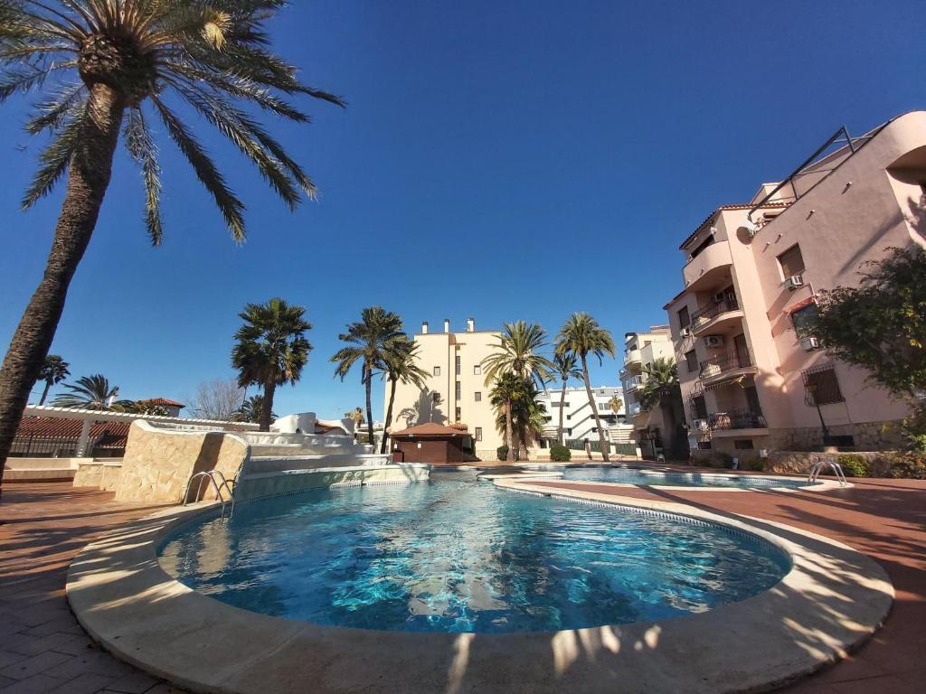 una piscina con palmeras y edificios en El retiro Denia, en Denia