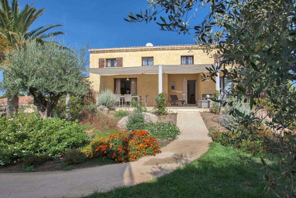 una casa con un jardín delante de ella en Appartement de vacances Arbousier à Calvi piscine chauffée partagée bbq en Calvi