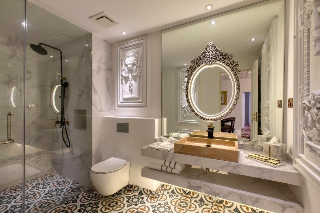 A marble bathroom with a glass-enclosed shower, toilet and ornate vanity.