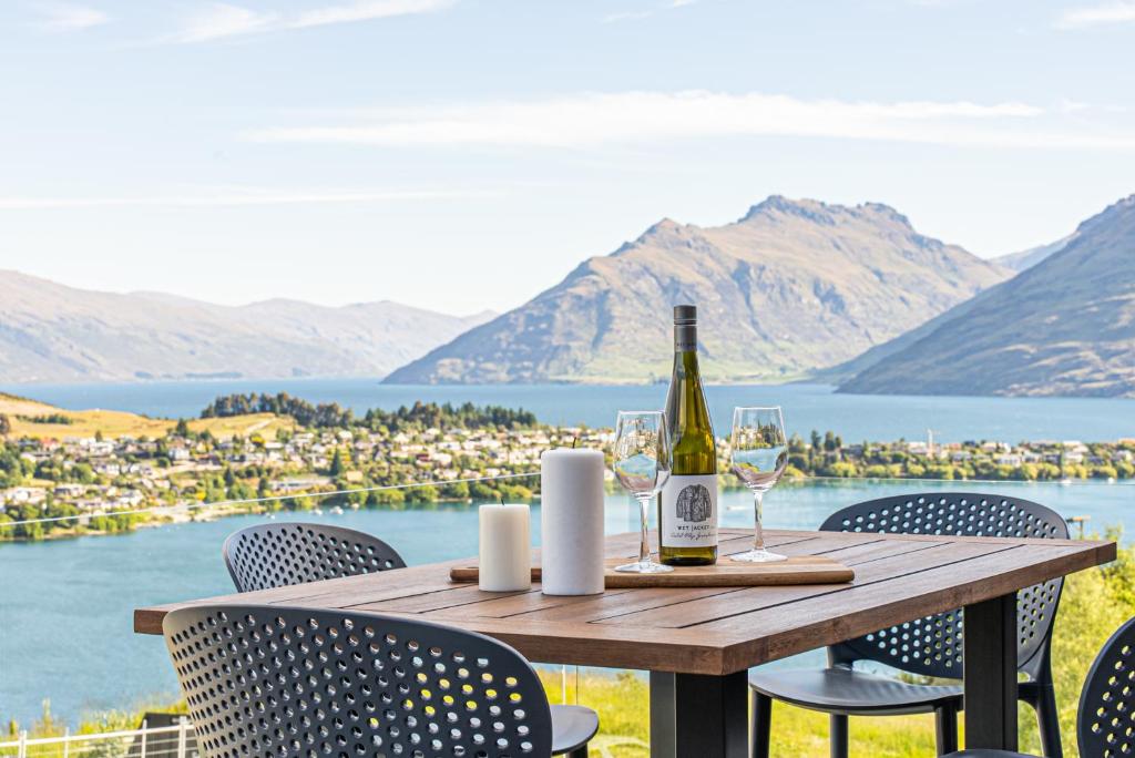 a bottle of wine sitting on a wooden table with chairs at Queenstown Lake and Mountain View Retreat Free Wifi Free Street Parking in Queenstown