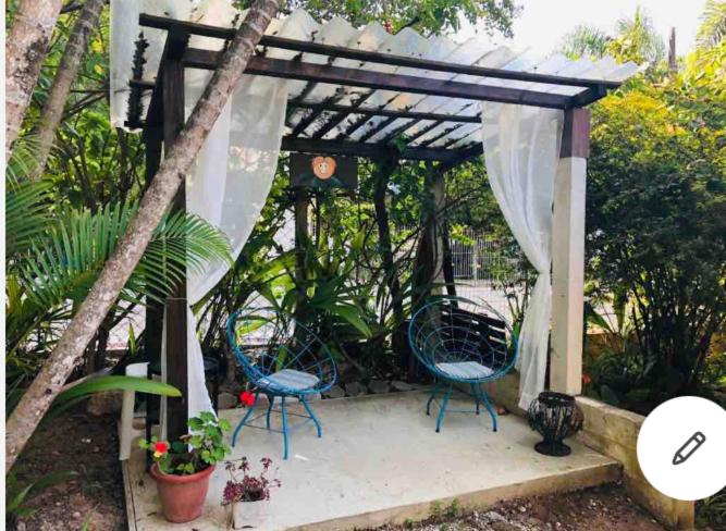 una pérgola con 2 sillas y una mesa en Casa Mico Leão Dourado, en Bombinhas